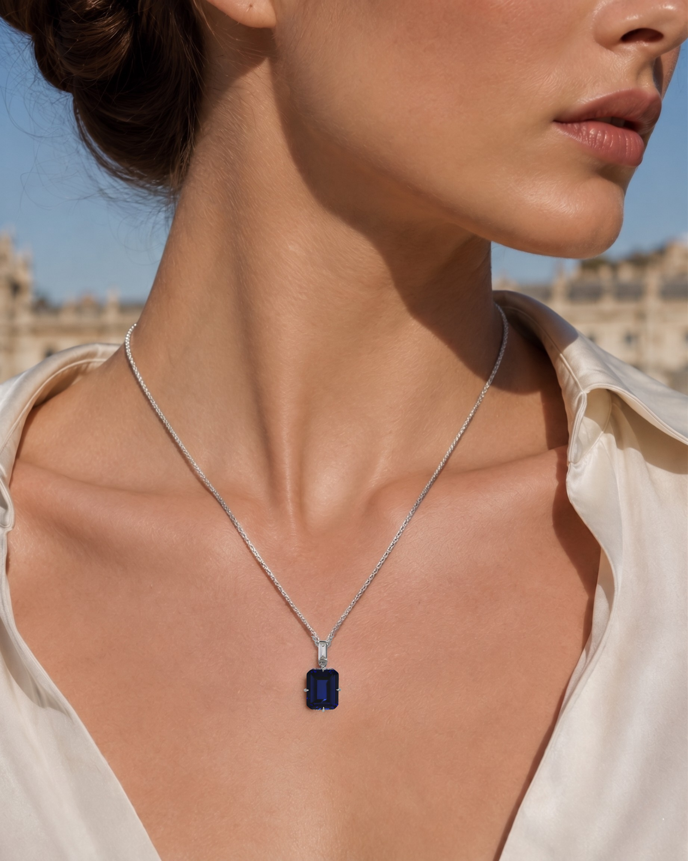 A model wears the London Bridge Blue Sapphire Pendant, featuring an emerald-cut sapphire on a silver chain.
