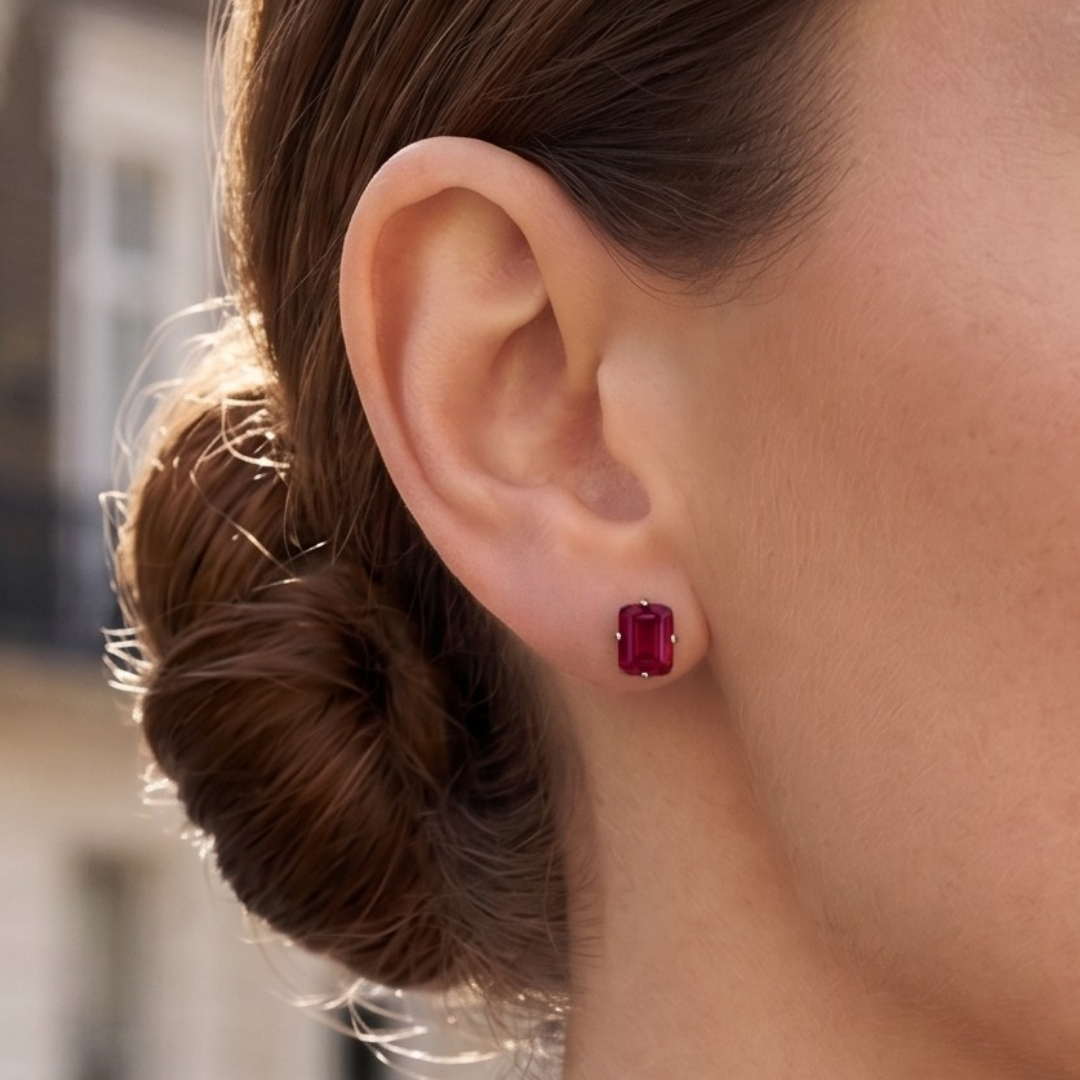 A close-up of a model's ear, wearing an emerald-cut ruby stud earring from the Lark & Berry London Bridge collection.