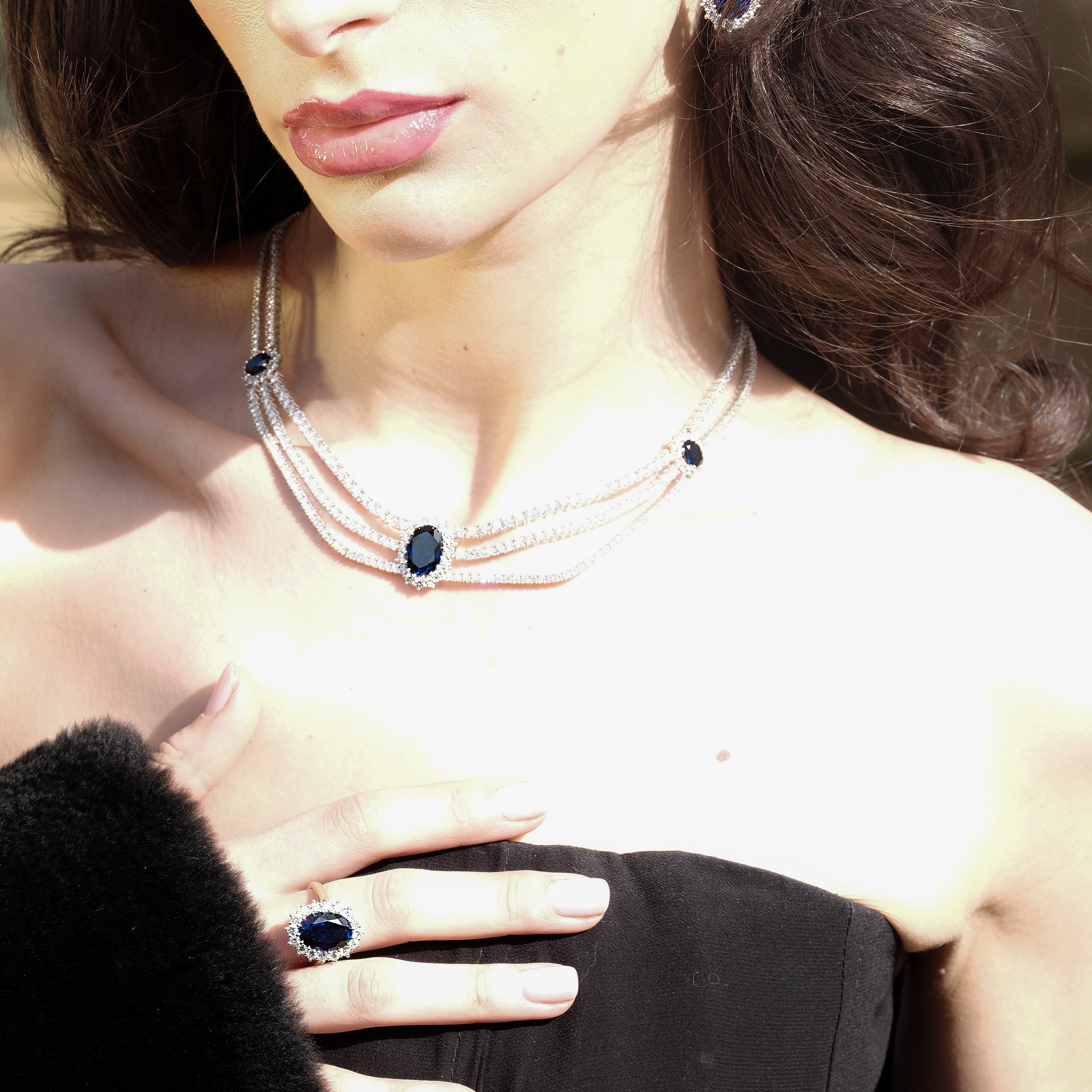 A woman wearing the Lark & Berry Kensington Ring, part of a stunning sapphire and diamond halo jewelry set.