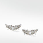 A pair of Lark & Berry Dove Duet white gold earrings with a cluster of baguette and round diamonds in a curved wing design.