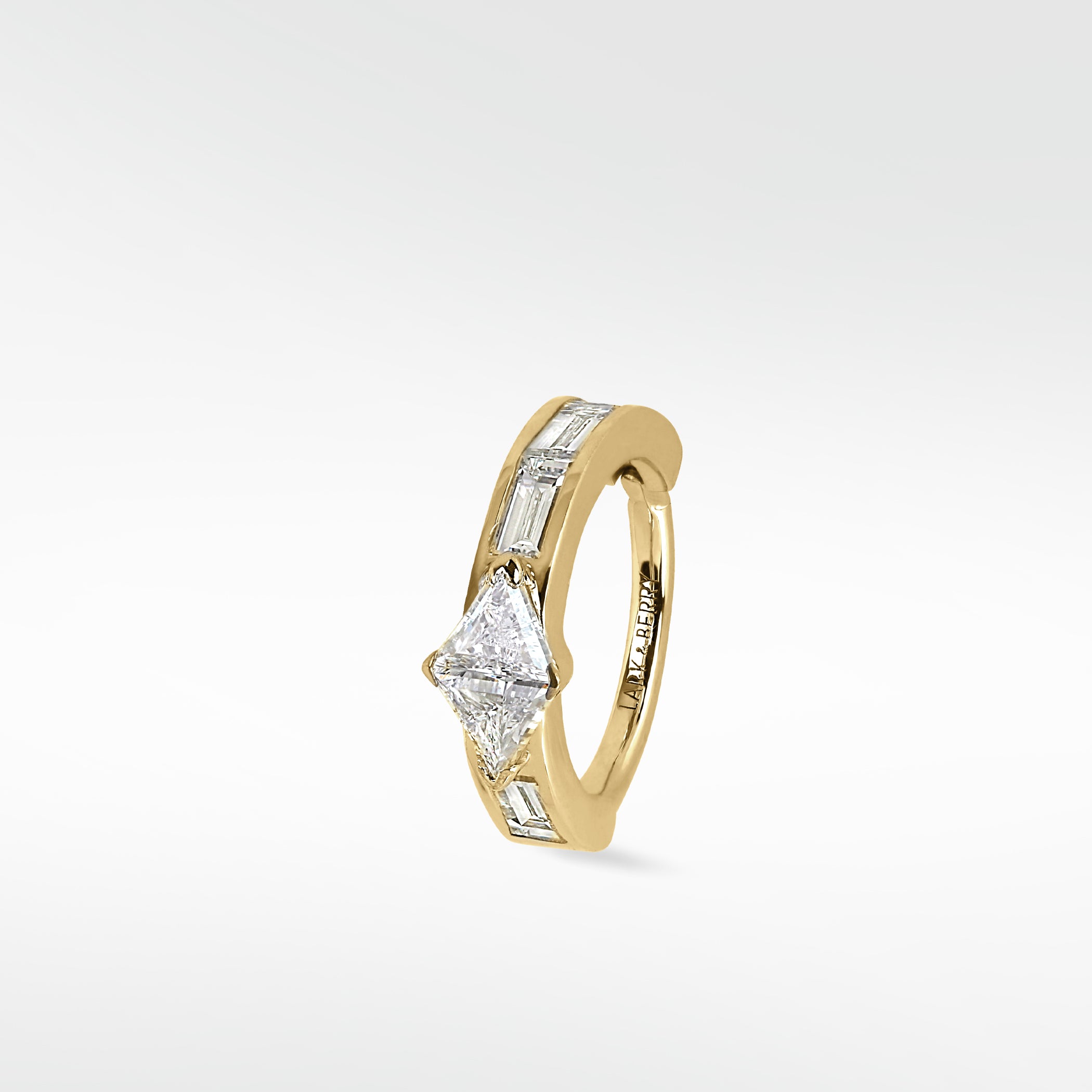 A yellow gold Modernist hoop earring featuring a central triangle diamond and channel-set baguette diamonds on a white background.