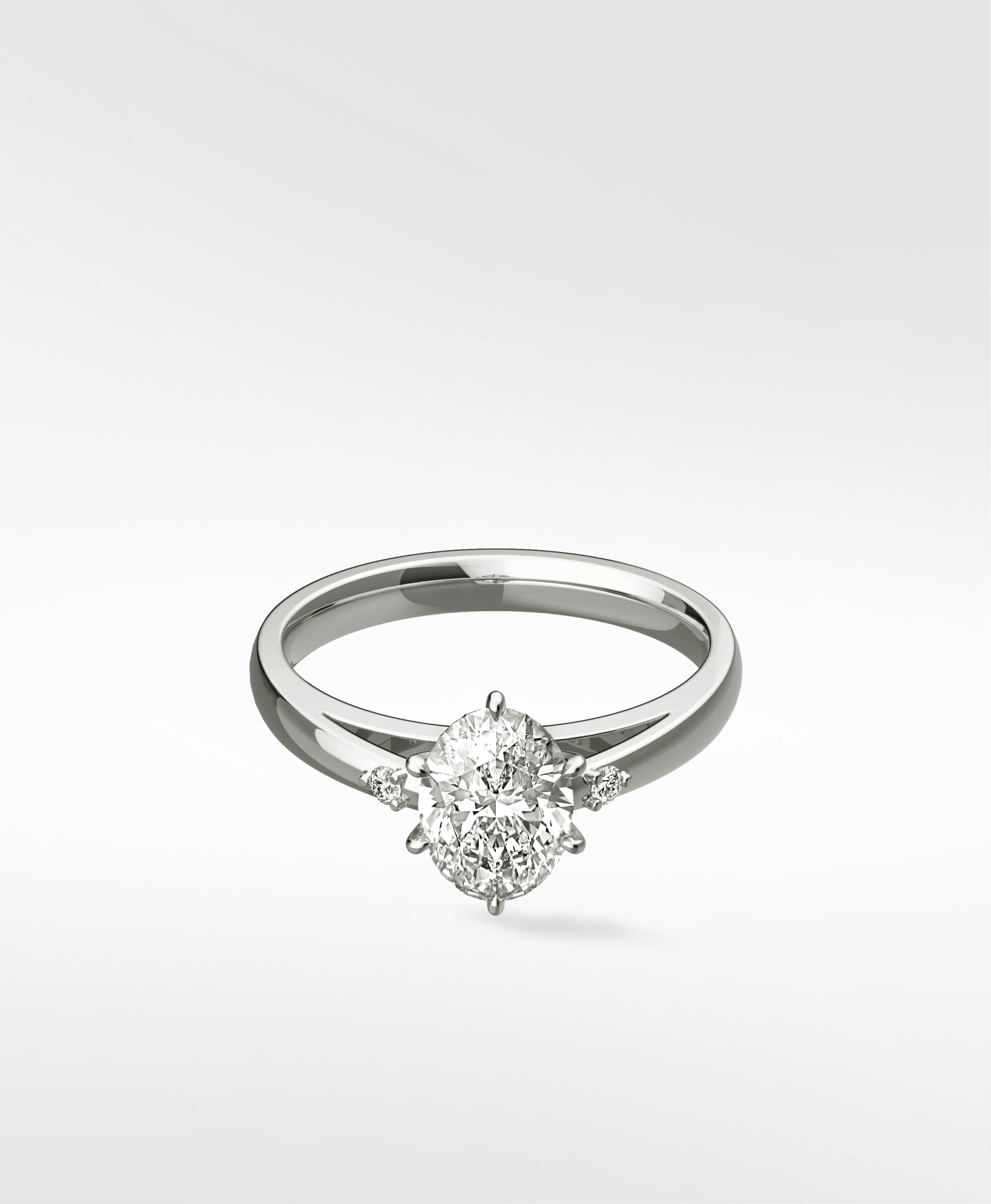 The Kentia Engagement Ring in white gold, featuring a brilliant oval diamond flanked by two smaller accent diamonds.