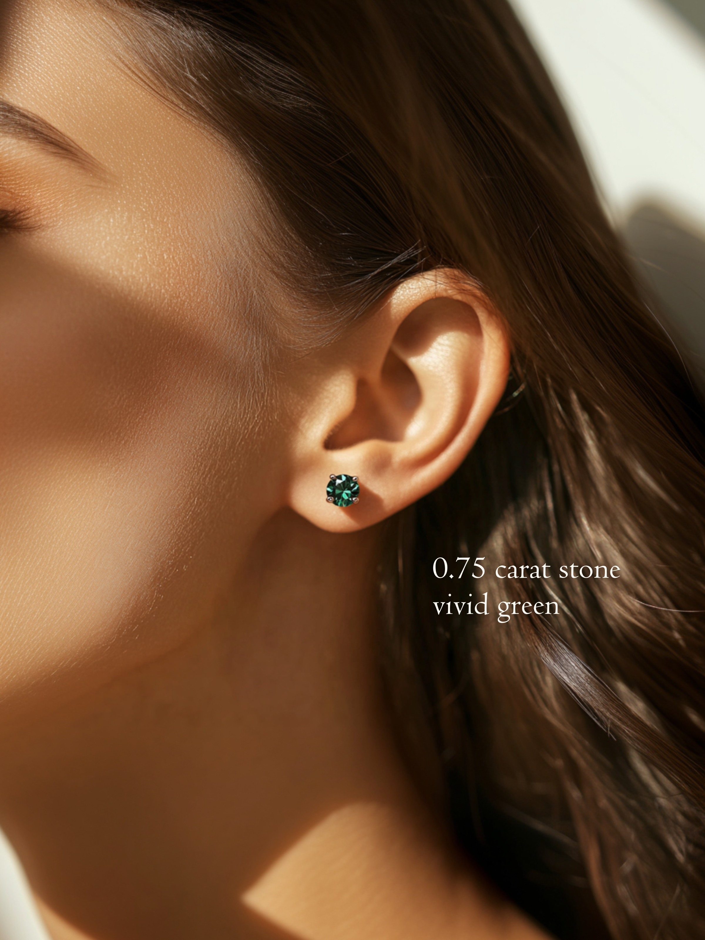 Close-up of a model's ear showing a brilliant round-cut, vivid green 0.75 carat diamond stud earring.
