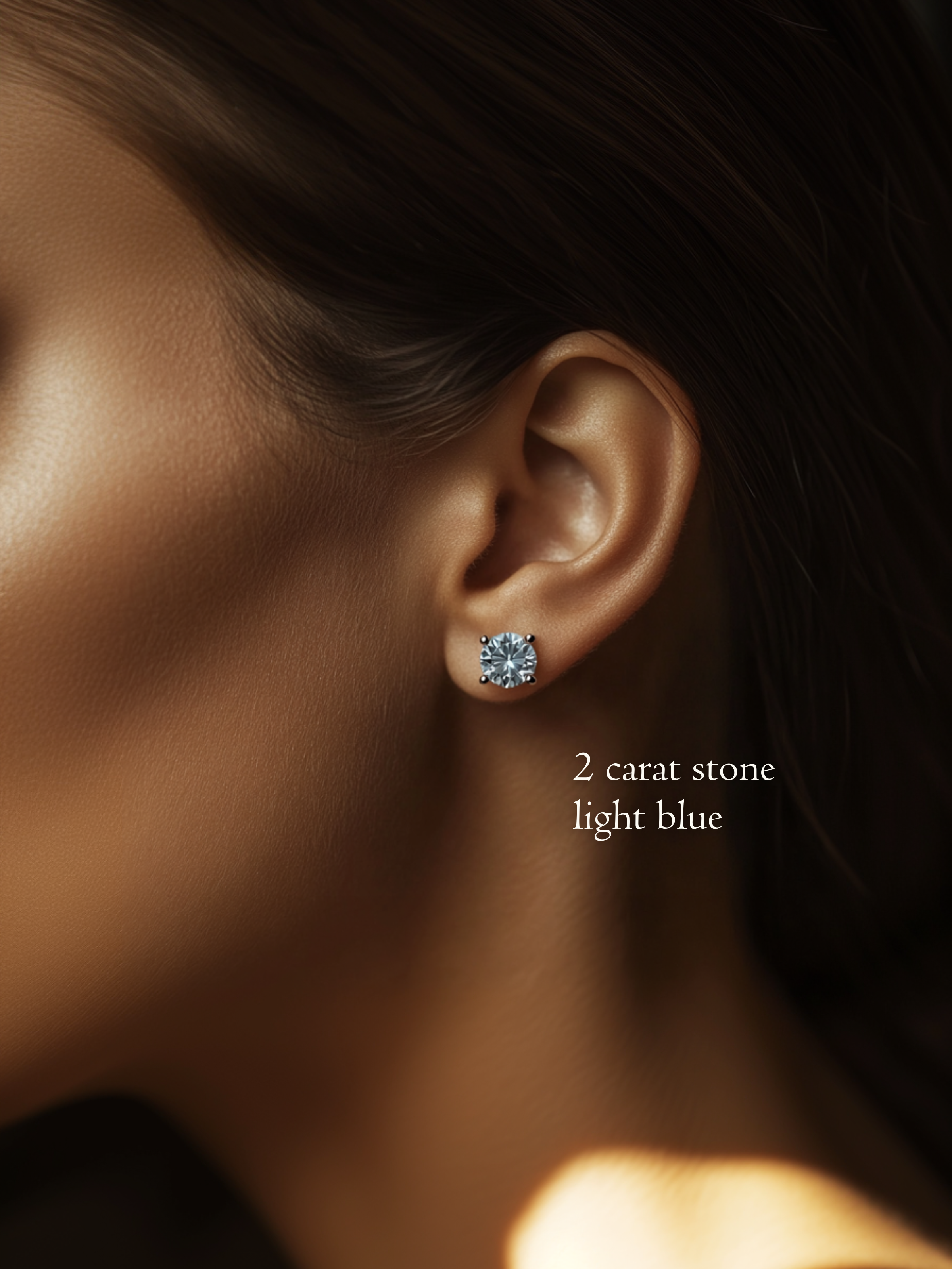 Close-up on a model's ear wearing a 2 carat, brilliant round cut, light blue diamond stud earring.