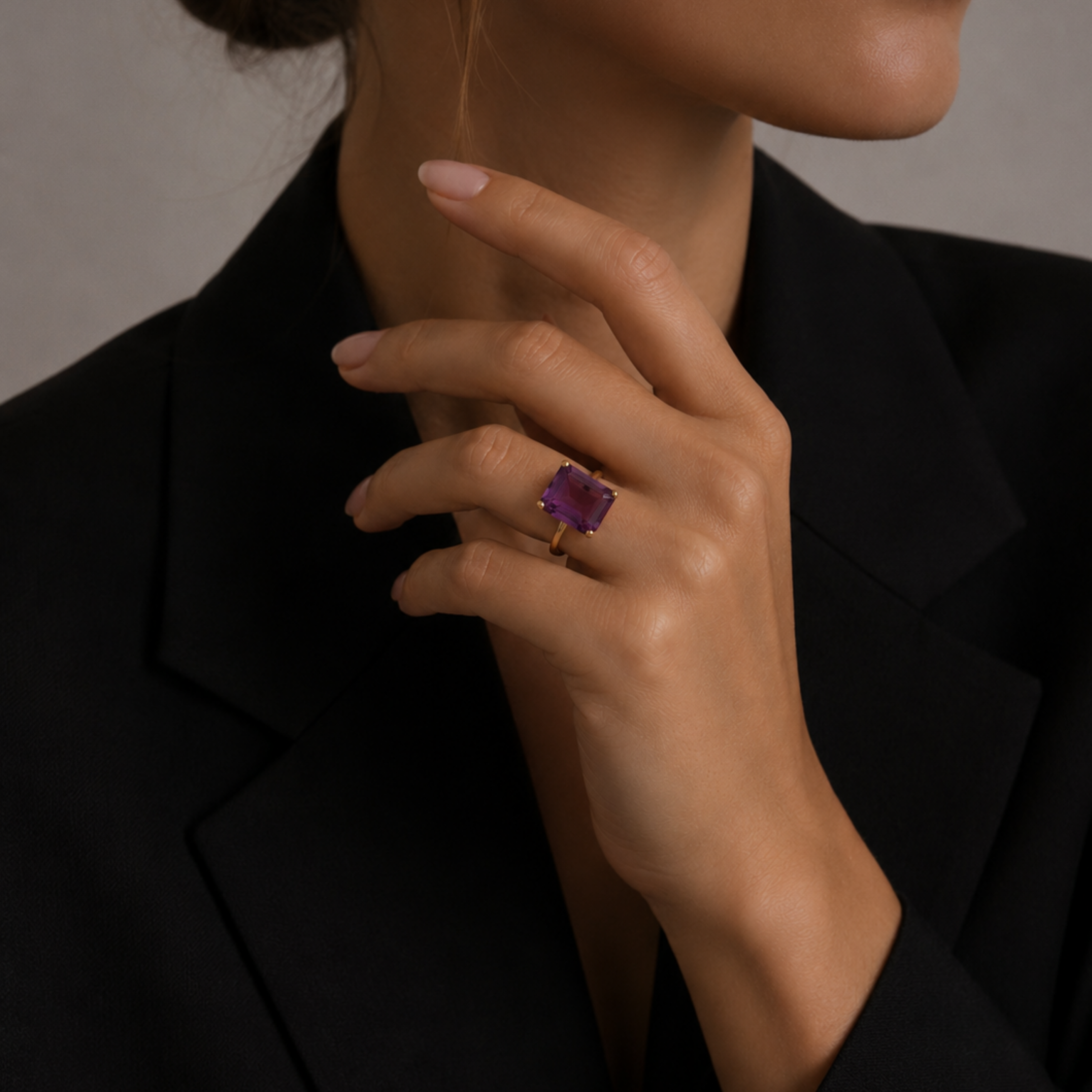 Model wearing the London Bridge Fancy Purple Sapphire Ring with a gold band, her hand resting against a black blazer.