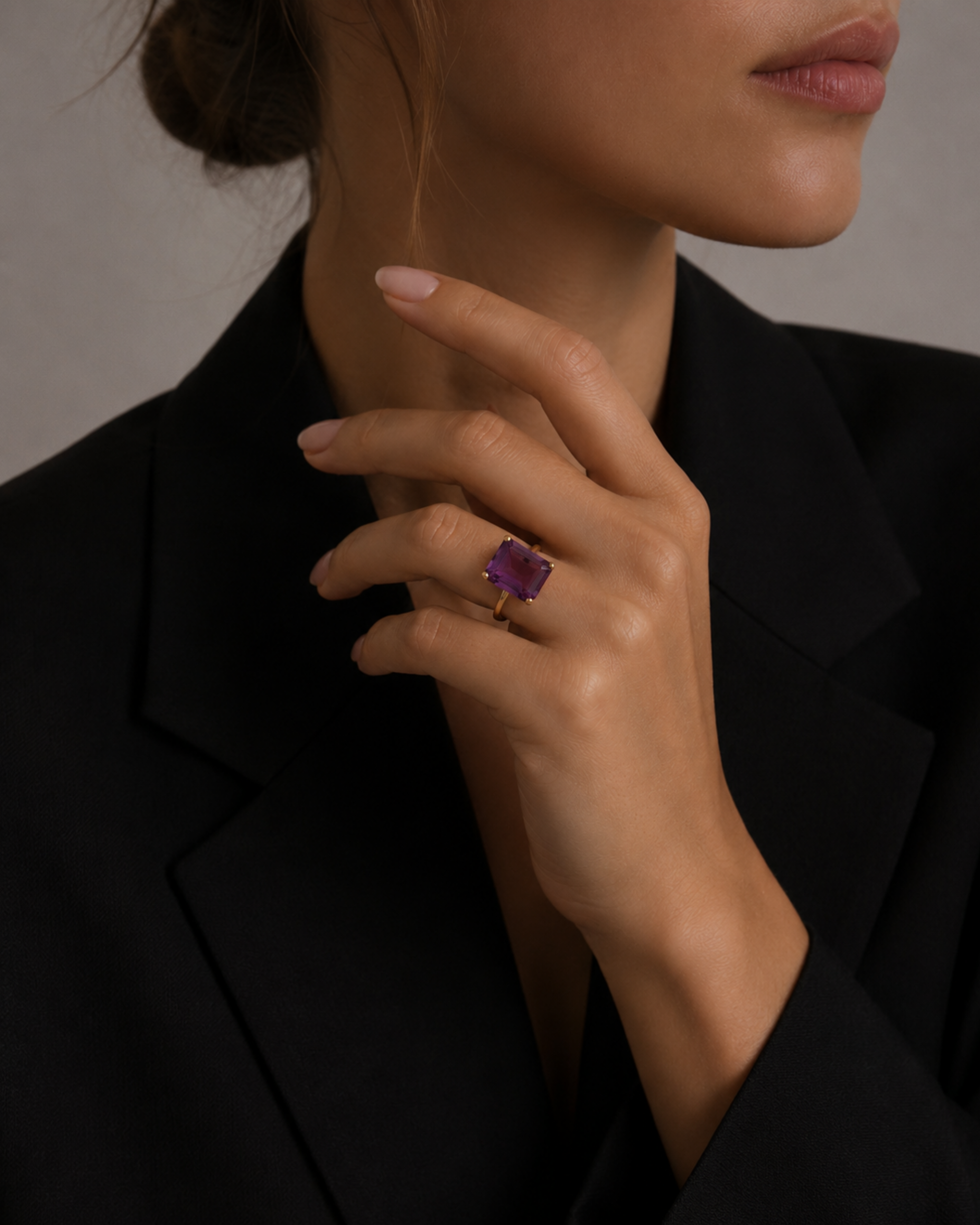 Model wearing the London Bridge Fancy Purple Sapphire Ring with a gold band, her hand resting against a black blazer.