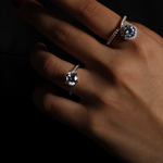The Lark & Berry Wild Cherry Diamond Engagement Ring with a halo setting, modeled on a hand against a dark background.