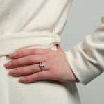 A model's hand with the Chestnut Diamond Engagement Ring, featuring a marquise-cut stone, resting on a cream coat.