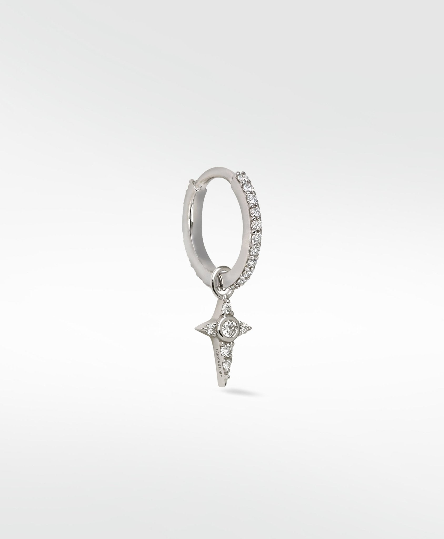 Lark & Berry Celestial Diamond Charm, a diamond star, hanging from a pavé diamond white gold hoop earring on a white background.