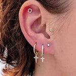 Close-up of a curated ear featuring a gold Celestial Diamond star charm on a hoop, styled with other diamond earrings and studs.