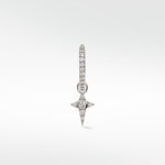 A Celestial Diamond Charm in white gold with a pavé star design hanging from a small diamond hoop earring.