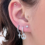 A close-up of an ear styled with a Celestial Diamond Charm on a silver hoop, paired with other diamond earrings and studs.