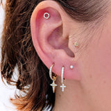 Close-up of a curated ear with Lark & Berry's gold Celestial Diamond star charm, a cross charm hoop, and various diamond studs.