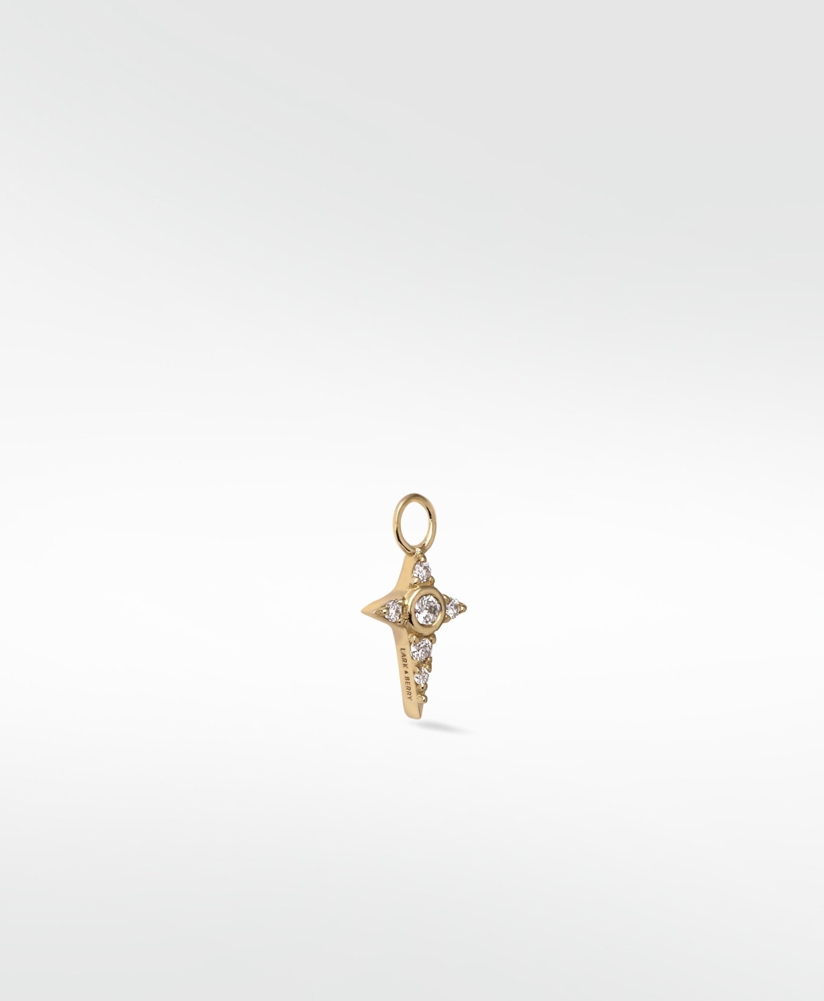 Lark & Berry's Celestial Diamond Charm in a gold, four-pointed star design set with a central round diamond and smaller accents.
